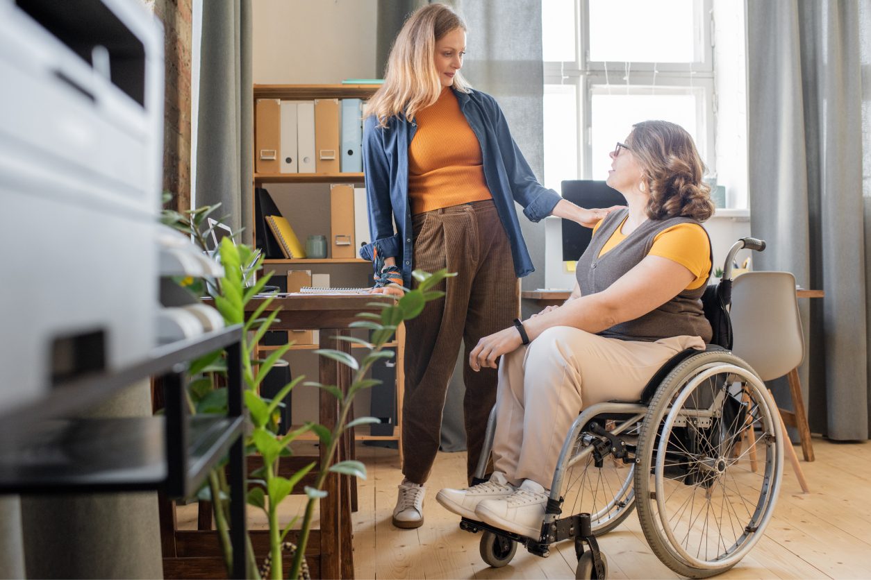 Two women talking, one in wheelchair.