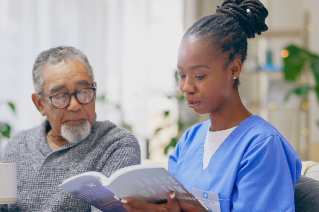 Nurse and elderly man reviewing a book together in a calm setting.