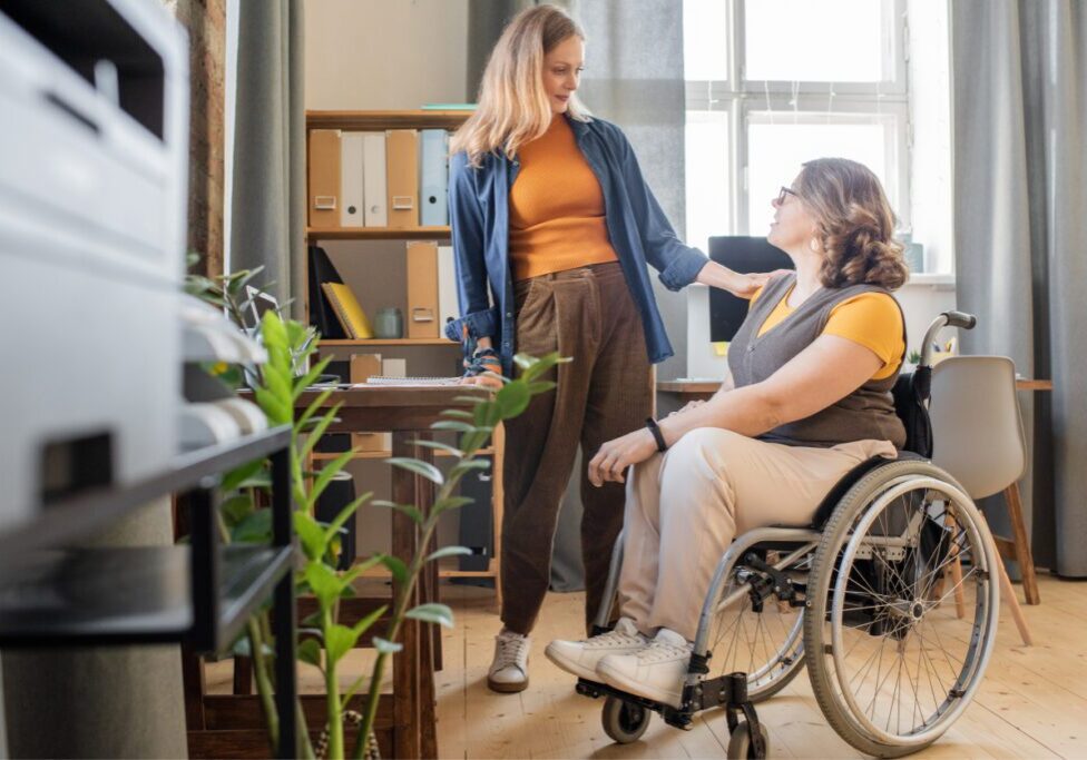 Two women talking, one in wheelchair.